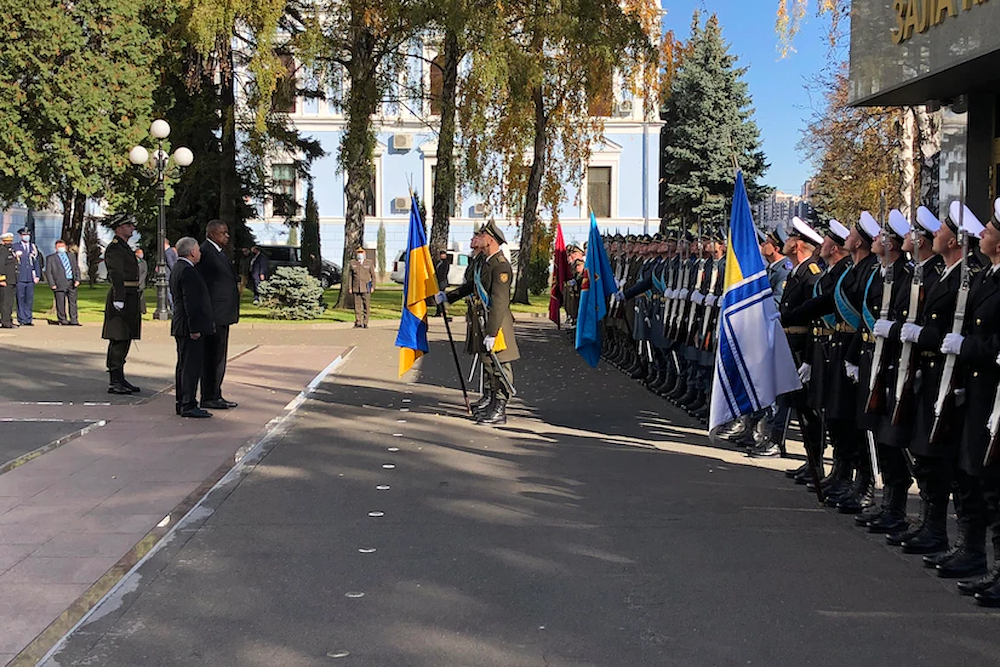 Two men face a line of soldiers holding flags.